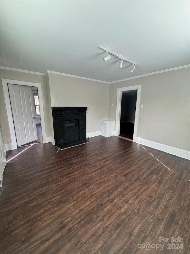 unfurnished living room featuring crown molding, rail lighting, and dark hardwood / wood-style floors