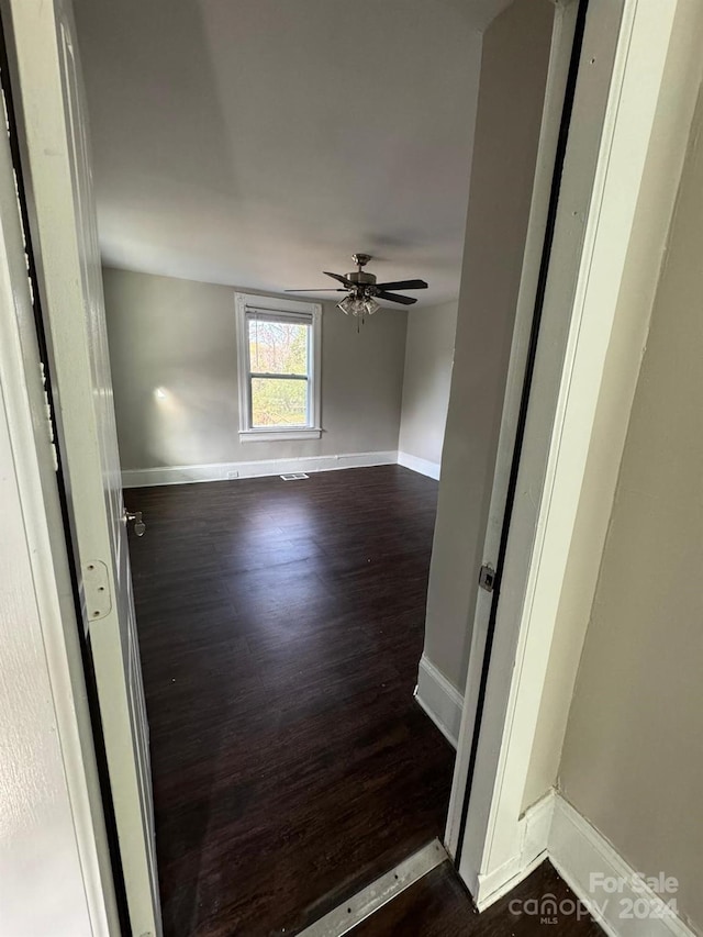 empty room with ceiling fan and dark hardwood / wood-style floors