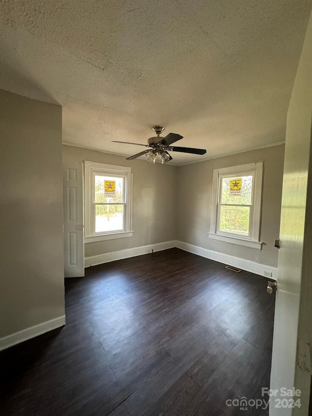 empty room featuring a textured ceiling, dark hardwood / wood-style floors, a wealth of natural light, and ceiling fan