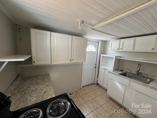 clothes washing area with sink, light tile patterned floors, and cabinets