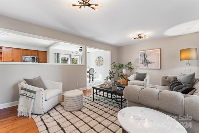 living room with ceiling fan with notable chandelier and light hardwood / wood-style floors