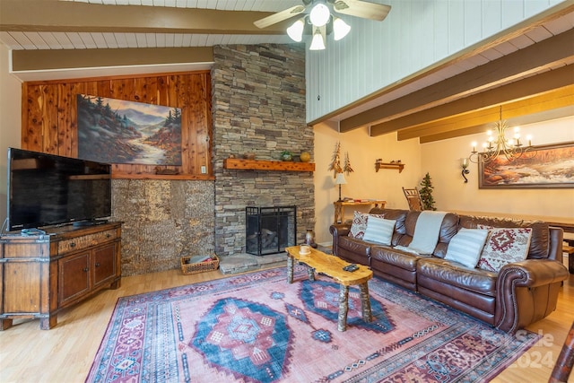 living room featuring a stone fireplace, light hardwood / wood-style flooring, lofted ceiling with beams, wooden walls, and ceiling fan with notable chandelier