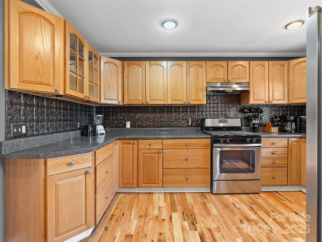 kitchen featuring gas stove, glass insert cabinets, under cabinet range hood, and light wood finished floors