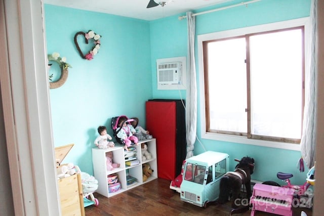 game room featuring ceiling fan, dark wood-type flooring, and a wall mounted AC