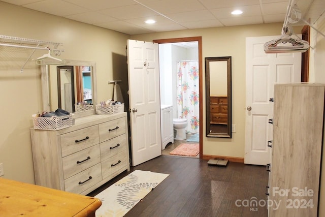 interior space featuring hardwood / wood-style flooring, a drop ceiling, and toilet