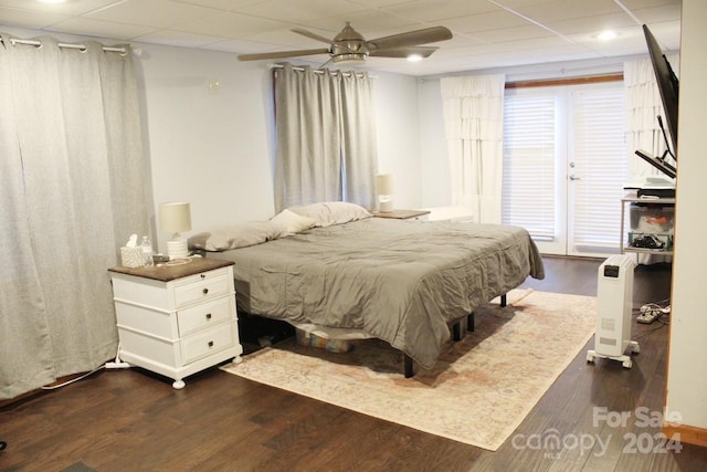 bedroom featuring ceiling fan, dark hardwood / wood-style flooring, and a drop ceiling