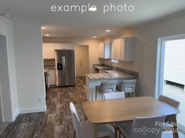 kitchen featuring white cabinetry, stainless steel appliances, dark hardwood / wood-style flooring, kitchen peninsula, and a breakfast bar