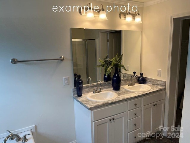 bathroom with vanity, a shower with door, and crown molding