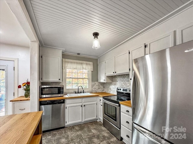 kitchen featuring sink, wooden counters, crown molding, white cabinets, and appliances with stainless steel finishes