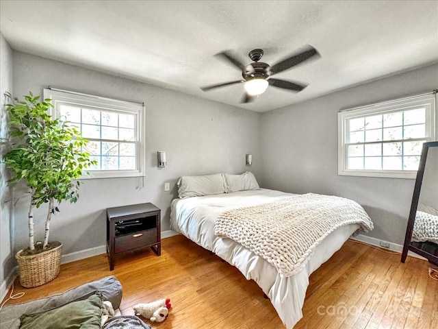 bedroom with wood-type flooring, multiple windows, and ceiling fan