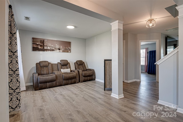 home theater room with decorative columns and light hardwood / wood-style floors