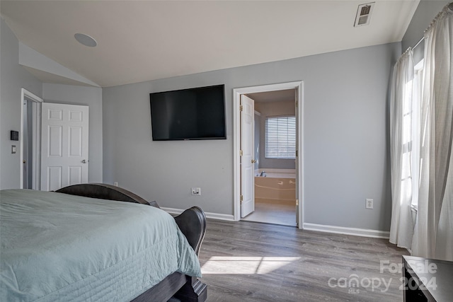 bedroom featuring connected bathroom, light hardwood / wood-style flooring, and lofted ceiling