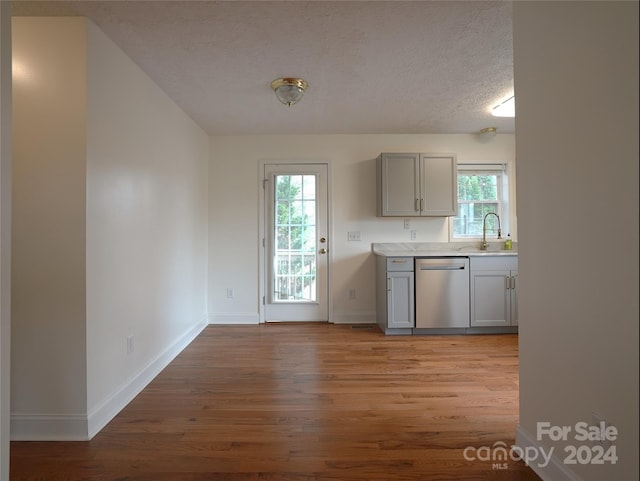 kitchen featuring gray cabinetry, dishwasher, sink, a textured ceiling, and light hardwood / wood-style floors