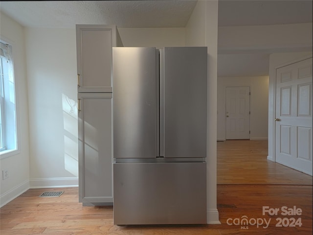 kitchen with stainless steel fridge, light hardwood / wood-style flooring, and a textured ceiling