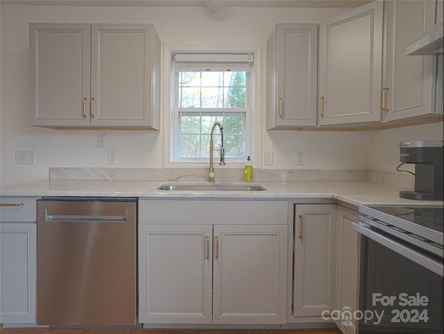 kitchen featuring appliances with stainless steel finishes, light stone counters, and sink