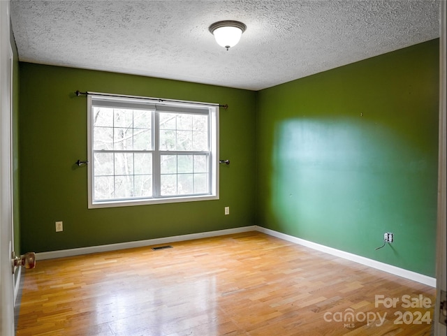 spare room with light hardwood / wood-style floors and a textured ceiling