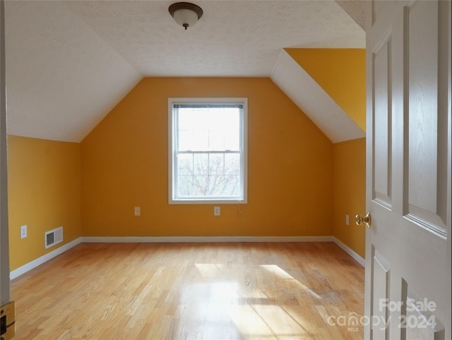 bonus room featuring a textured ceiling, light hardwood / wood-style floors, and lofted ceiling