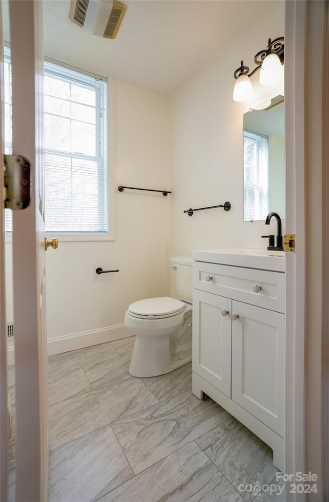 bathroom featuring vanity, toilet, and a wealth of natural light