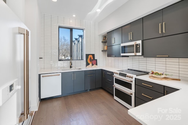 kitchen with premium appliances, sink, dark hardwood / wood-style flooring, and tasteful backsplash