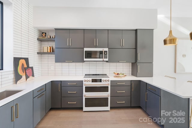 kitchen featuring white appliances, gray cabinetry, hanging light fixtures, and decorative backsplash