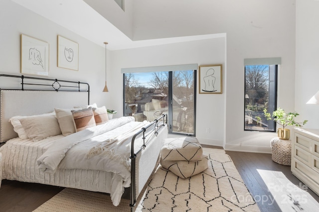 bedroom with hardwood / wood-style floors, multiple windows, access to outside, and a high ceiling