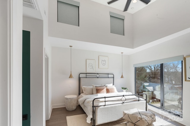 bedroom featuring wood-type flooring, access to exterior, and a towering ceiling