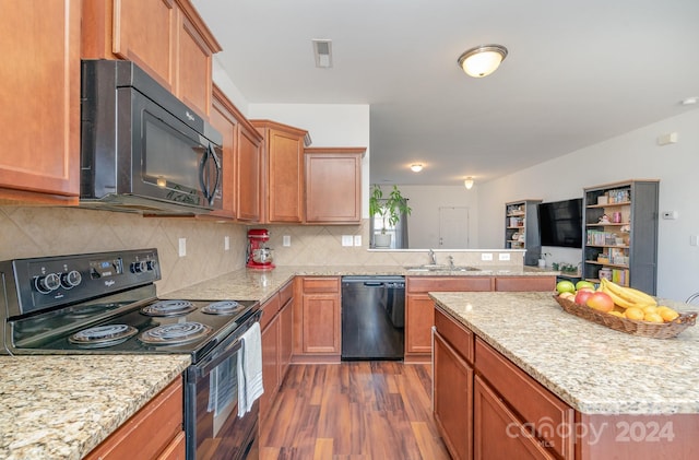 kitchen with light stone countertops, dark hardwood / wood-style flooring, tasteful backsplash, sink, and black appliances