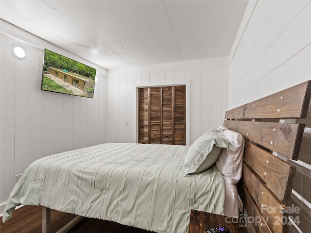 bedroom with hardwood / wood-style floors, a closet, and wooden walls