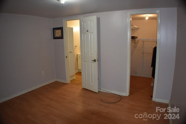 unfurnished bedroom featuring a walk in closet, light hardwood / wood-style floors, and a closet