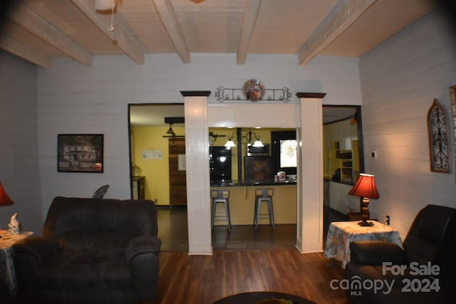 living room featuring beam ceiling, wooden walls, and wood-type flooring