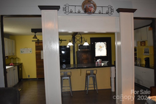 306 Mcadenville Rd, Lowell, NC 28098 - kitchen with stainless steel microwave, dark wood-style floors, a kitchen bar, and decorative columns