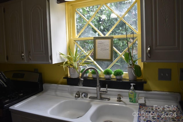 room details with dark brown cabinetry, white gas range, and sink