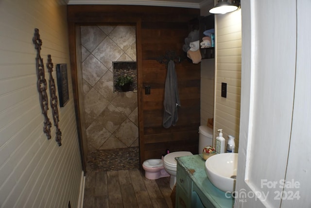 bathroom featuring walk in shower, wood walls, vanity, and hardwood / wood-style flooring