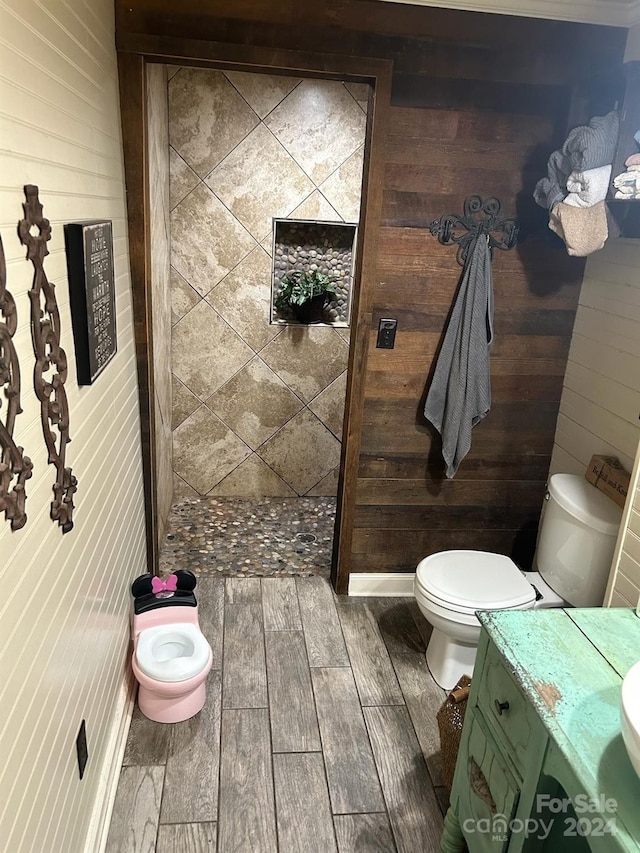 bathroom featuring vanity, hardwood / wood-style flooring, and wood walls