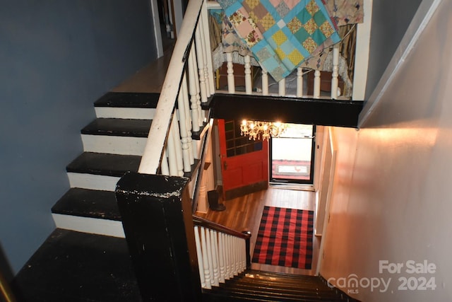 staircase with hardwood / wood-style flooring and an inviting chandelier