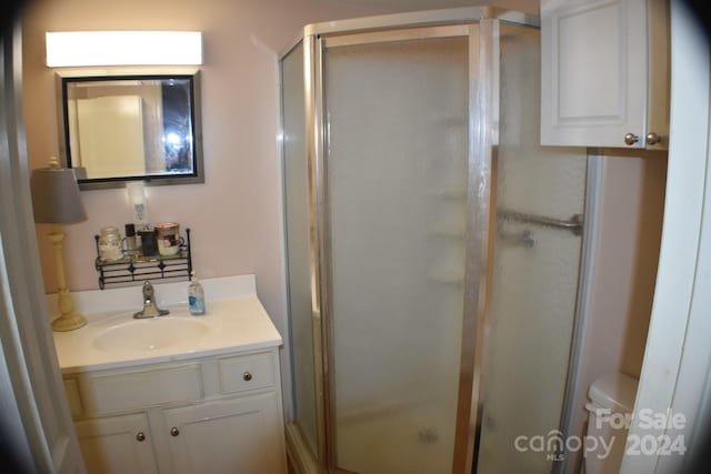 bathroom with a shower with door, vanity, and toilet