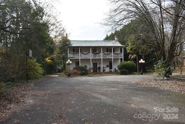 306 Mcadenville Rd, Lowell, NC 28098 - view of front of home featuring asphalt driveway, a porch, a balcony, and a metal roof