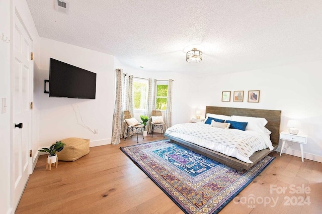 bedroom with hardwood / wood-style floors and a textured ceiling