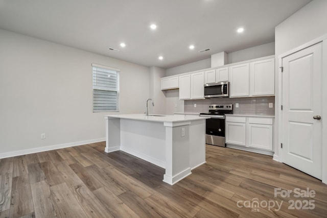 kitchen featuring backsplash, white cabinetry, a kitchen island with sink, and appliances with stainless steel finishes