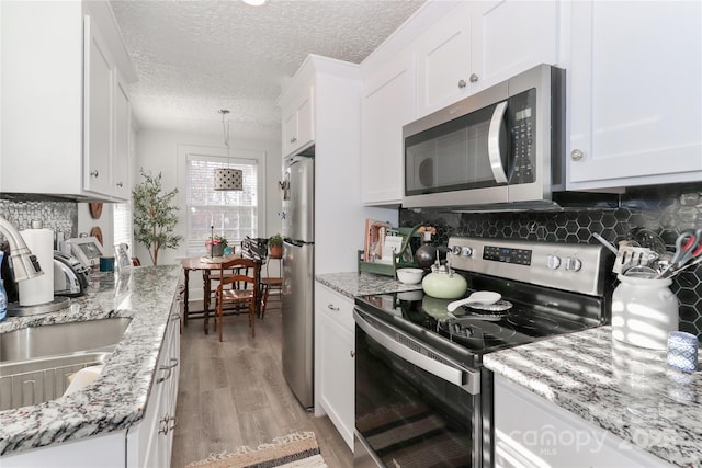 kitchen with appliances with stainless steel finishes, a textured ceiling, and white cabinetry