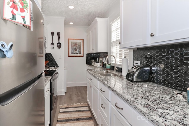 kitchen with decorative backsplash, stainless steel fridge, a textured ceiling, sink, and white cabinets