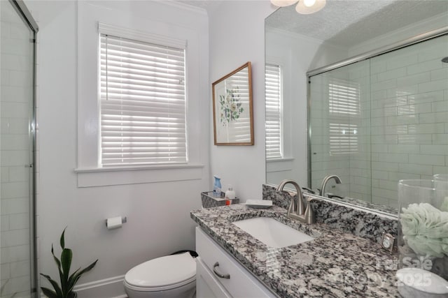 bathroom with vanity, crown molding, toilet, a textured ceiling, and walk in shower