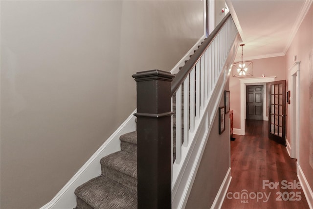 stairway with hardwood / wood-style flooring, ornamental molding, and an inviting chandelier