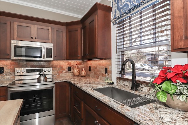 kitchen featuring light stone countertops, sink, stainless steel appliances, backsplash, and ornamental molding