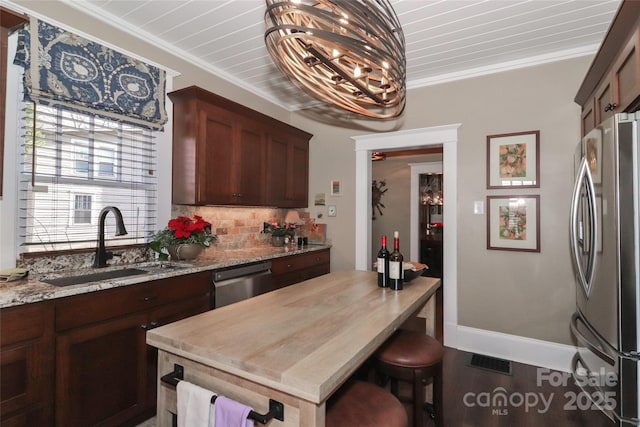 kitchen with crown molding, sink, light stone countertops, a notable chandelier, and stainless steel appliances