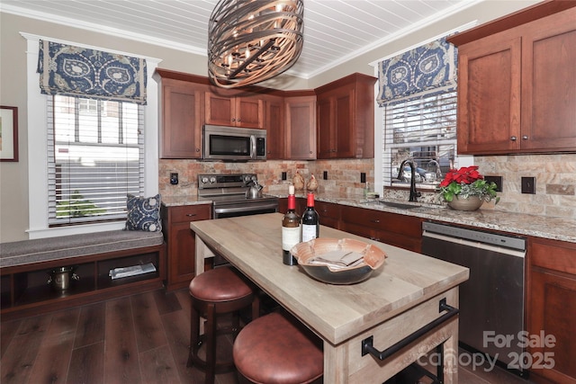 kitchen featuring sink, dark hardwood / wood-style floors, ornamental molding, light stone counters, and stainless steel appliances