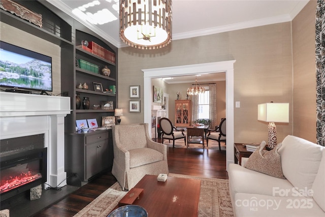 living room with built in shelves, dark hardwood / wood-style floors, crown molding, and a notable chandelier