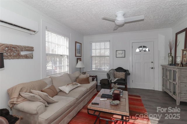 living room with dark wood-type flooring, an AC wall unit, ceiling fan, ornamental molding, and a textured ceiling