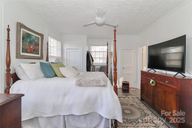 bedroom with light wood-type flooring, a textured ceiling, ceiling fan, and ornamental molding