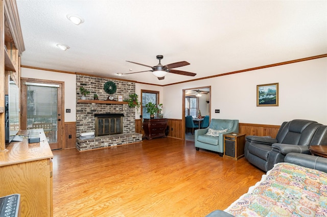 living room with hardwood / wood-style flooring, wood walls, ornamental molding, and a fireplace